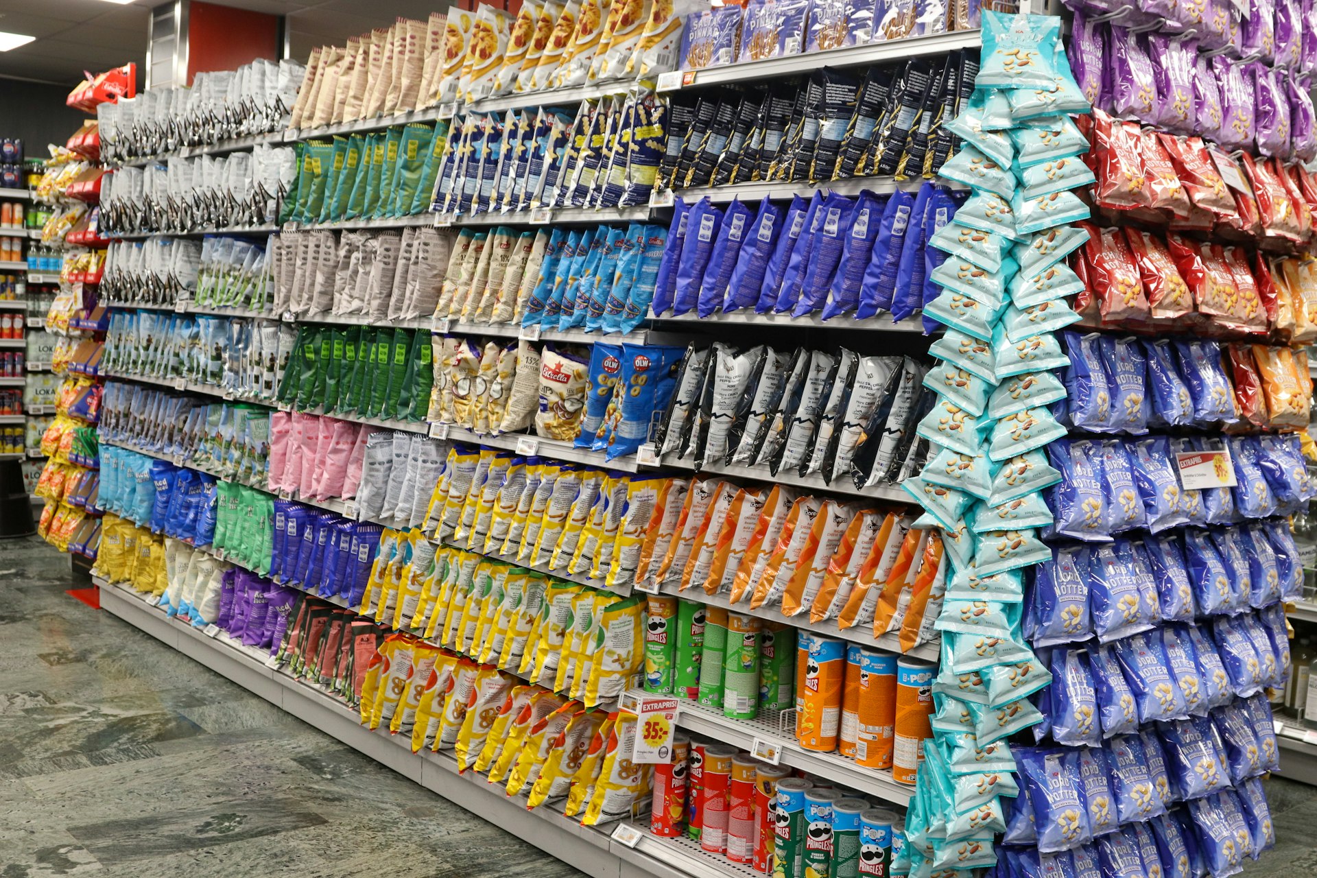 Shelves are stocked with colorful bags of snacks.